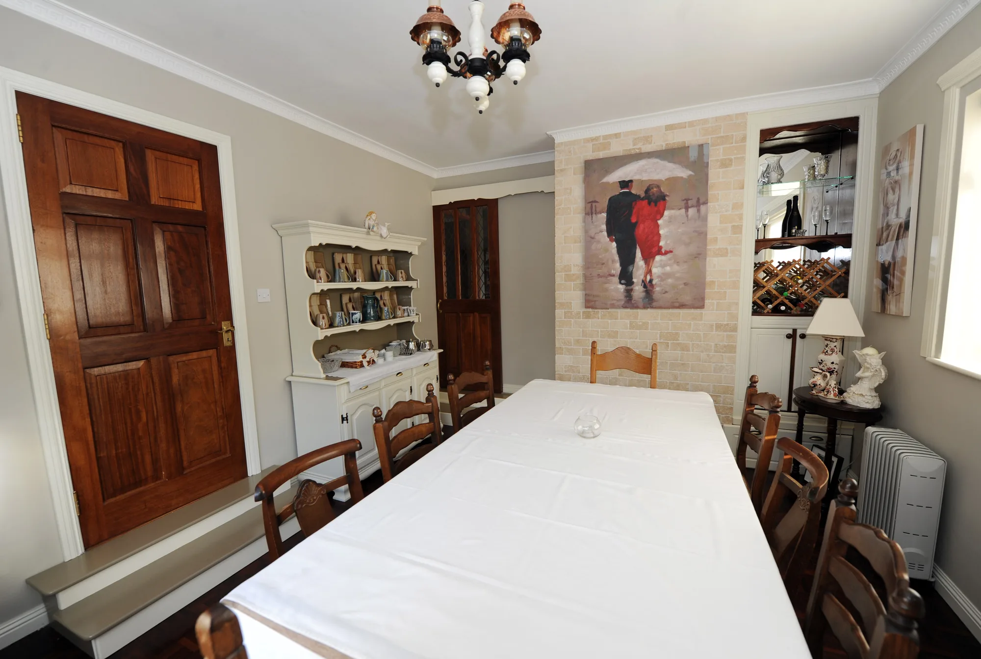 The dining room with a long table laid in white linen and a painted dresser