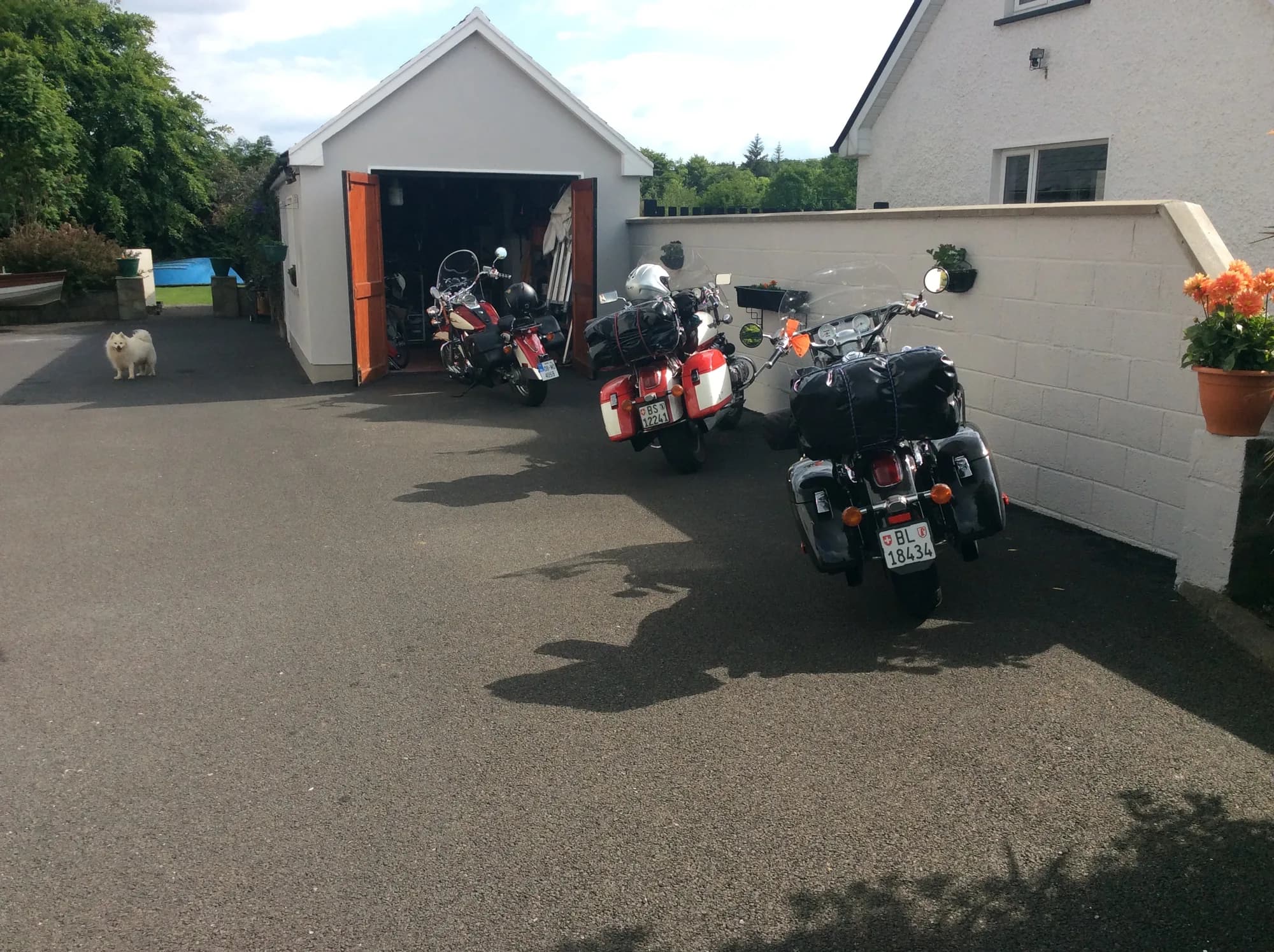 Three touring motorcycles parked in the driveway beside the open garage
